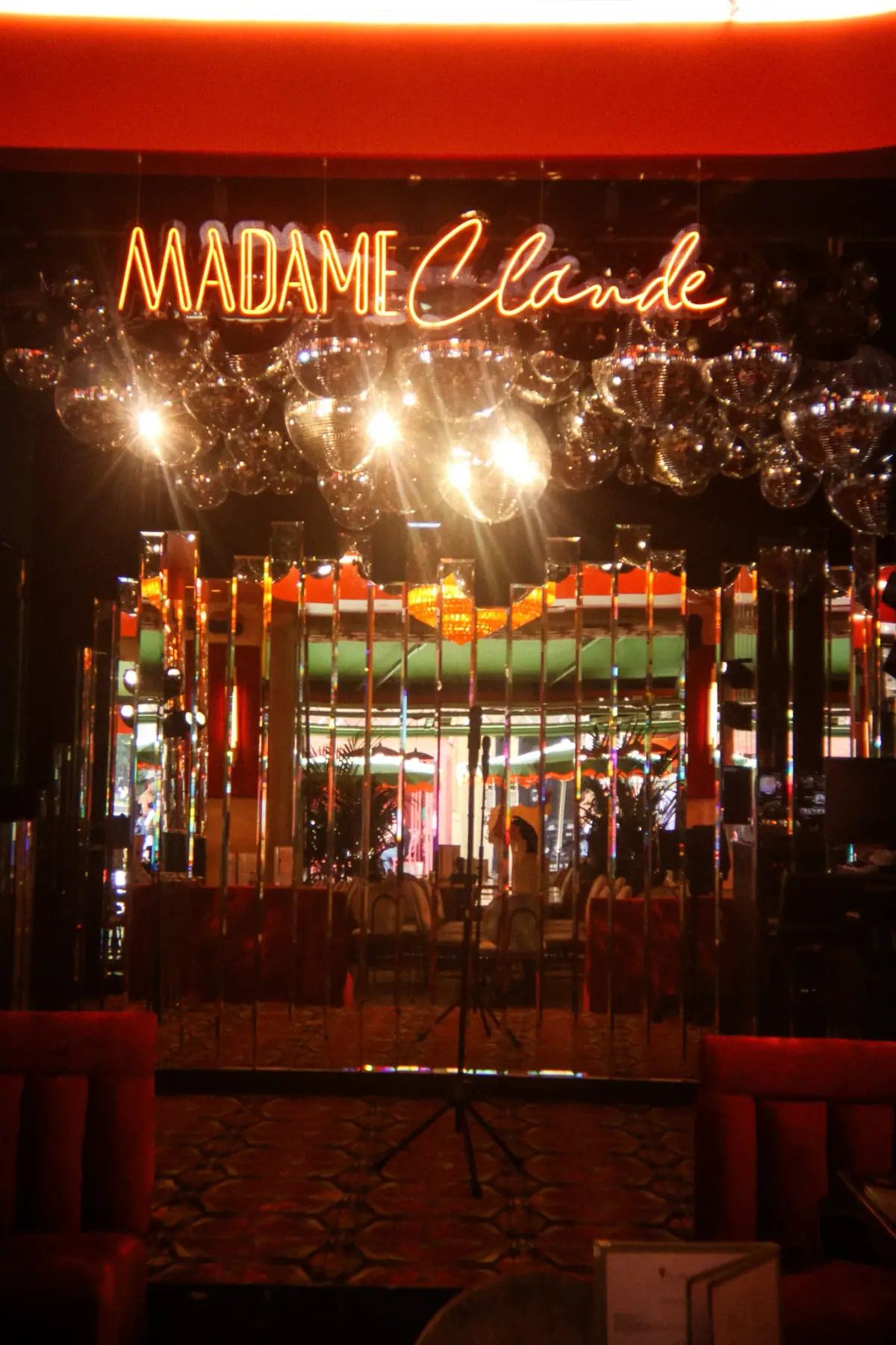 Madame Claude neon sign lighting up the karaoke stage, 1970s retro vibe