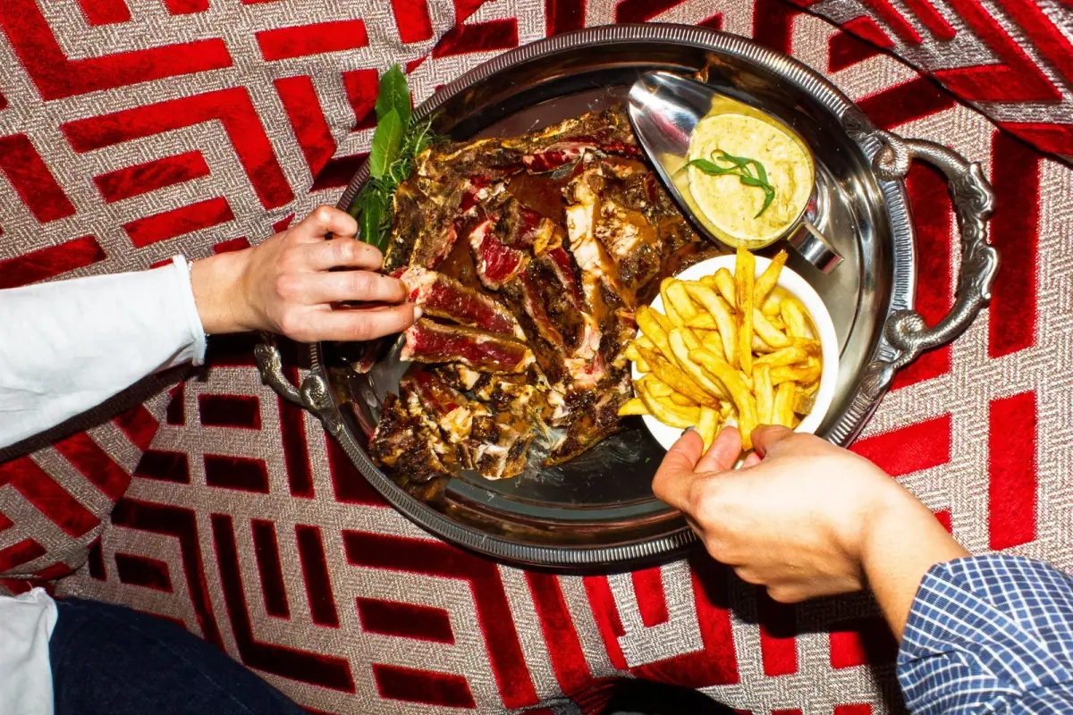 Signature grilled meat dish served at Madame Claude Paris, classic French cuisine in a 1970s retro setting