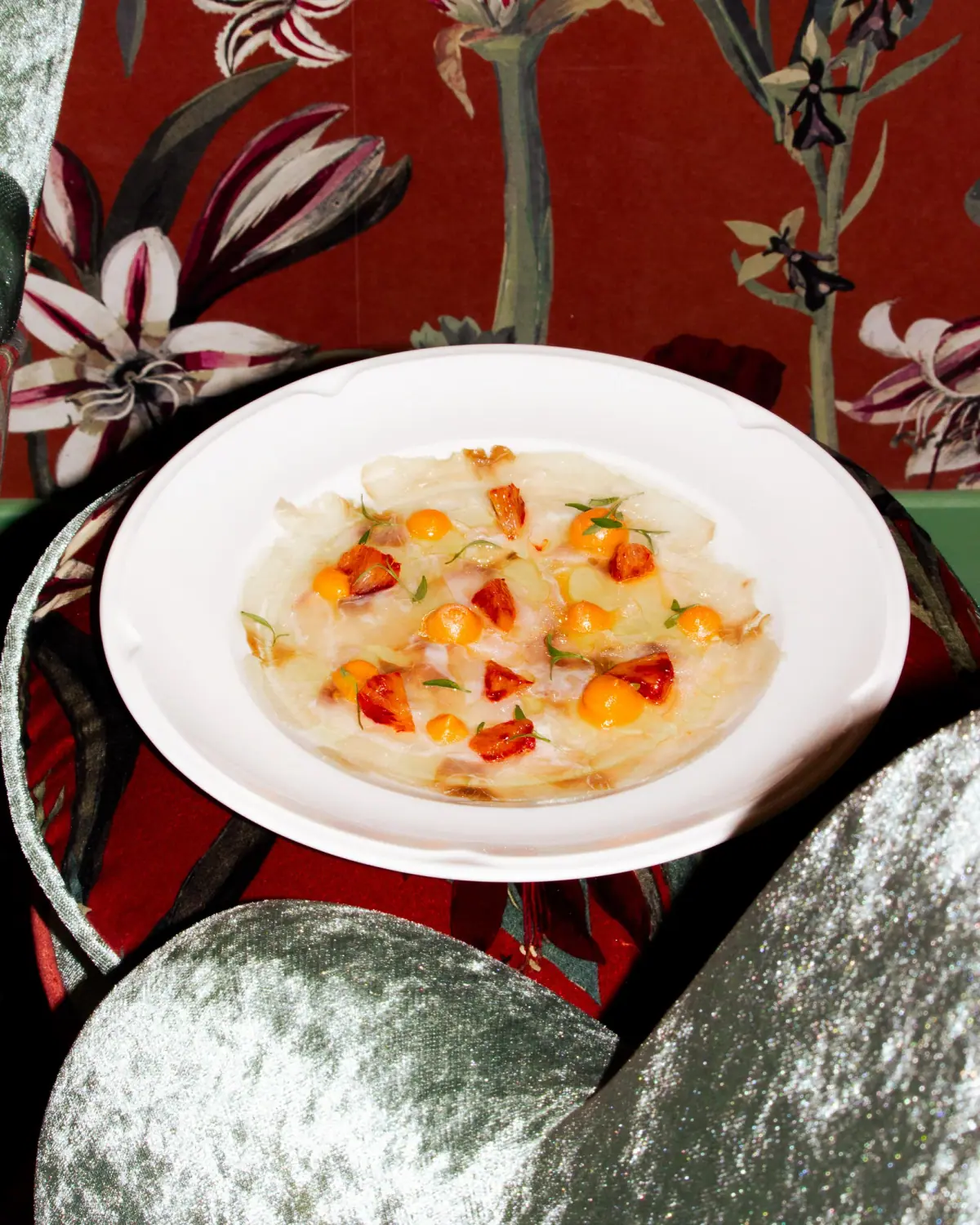 White fish carpaccio starter with physalis and fresh herbs.