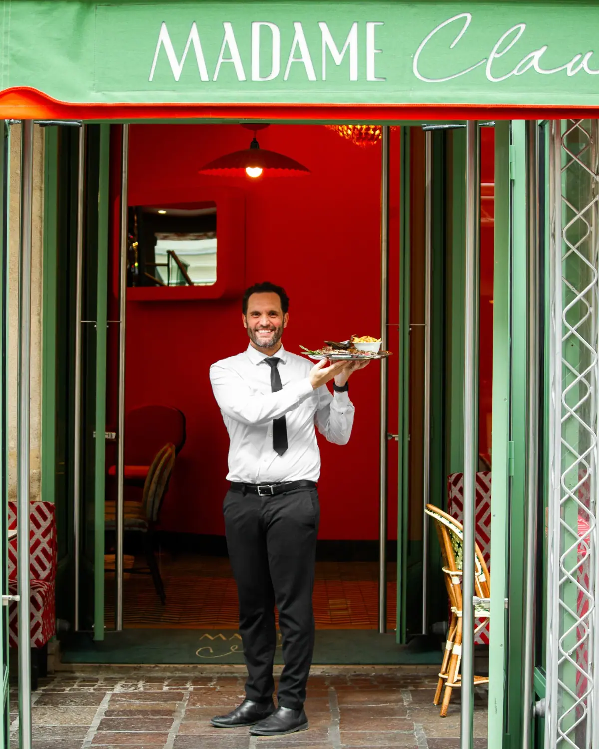 A smiling Madame Claude waiter presenting dishes of the day.