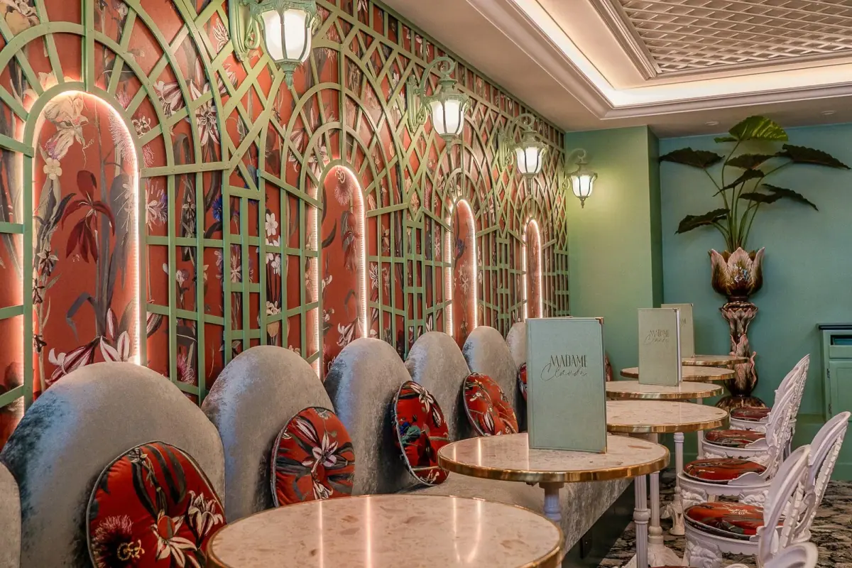 Intimate lower-level dining room at Madame Claude with velvet and 1970s floral decor