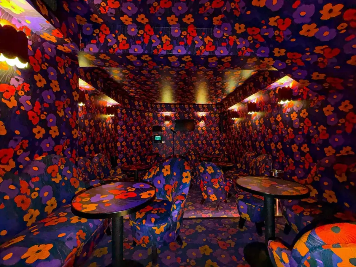The Poppy Room with lush floral decor, vintage round tables and 1970s upholstered chairs